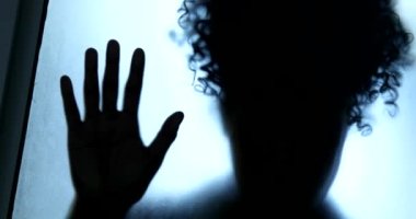 Depresyon konsepti, camın arkasında kapana kısılmış kadın gölgesi.