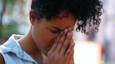 Stressed young black woman rubbing face with hands