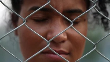 Sad depressed black woman behind metal fence feeling trapped