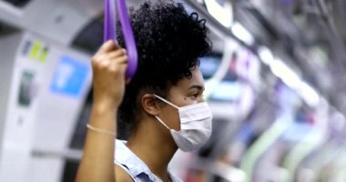Afrika kökenli Amerikalı kadın salgın sırasında metro tırabzanı tutuyor.