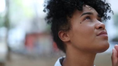Black woman looks at the sky with hope and faith