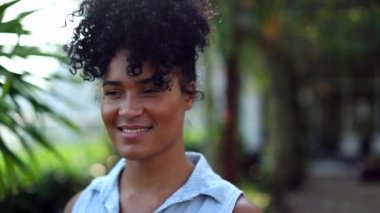 Thoughtful black woman standing outside in nature smiling