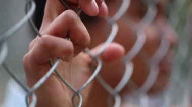 Hands holding metal fence close-up