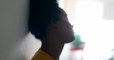 Düşünceli genç siyahi kadın duvara yaslanmış düşünüyor.