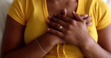 Young black woman putting hands on chest with faith and hope