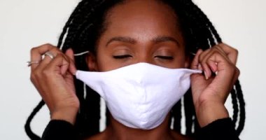 African teen girl removing face mask in relief. Person takes off mask