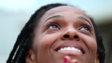 Black woman looking at sky with HOPE, African person closing eyes in meditation and contemplation