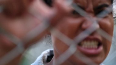 Angry black African woman locked behind metal fence bars