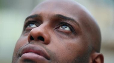 Contemplative black African man opening eyes looking up to sky