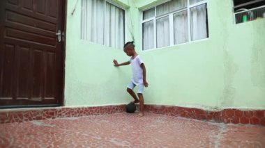 Mixed race child boy playing soccer by himself