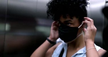 Siyahi kadın asansörün içine covid-19 yüz maskesi koyuyor