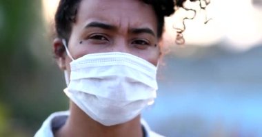 Yüz maskesi takan, yumruğunu kaldıran siyah kadın portresi.