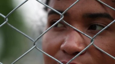 Mixed race woman metal bars holding into security gate