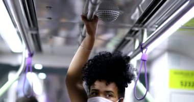 Metro tırabzanı tutan bir kadın. Kovid-19 yüz maskesi takıyor.