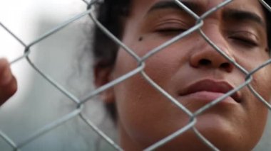 Mixed race woman behind fence. African person feeling trapped concept