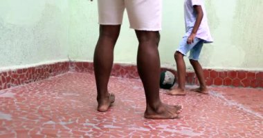 Afrikalı bir ebeveyn oğluyla top oynuyor. Çocuk sporla babasıyla bağ kuruyor.