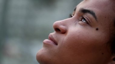 Mixed race woman looking up to sky closing eyes in contemplation