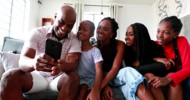 Black family taking selfie together, african parents and children using smartphone laughing and smiling