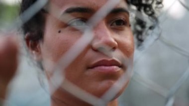 Black woman behind metal fence. African woman close-up face with grid gate in foreground