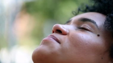 Young woman opening eyes outside looking up at sky