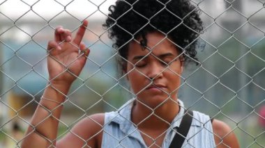 Mixed race woman behind fence. African person feeling trapped concept