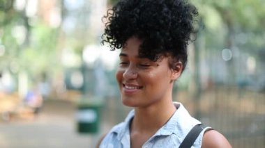 Casual millennial black woman standing outside scratching face