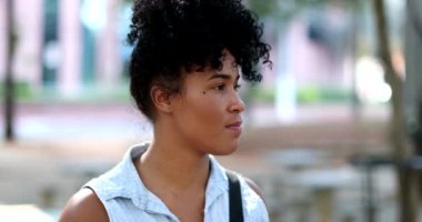 Pensive young mixed race woman standing outside