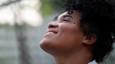 Black woman looking up to sky smiling. Hopeful happy African person
