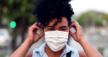 Mixed race woman putting covid-19 face mask outside in urban background