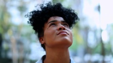 Hopeful Brazilian woman looking up to sky, portrait face