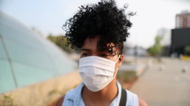 Young black woman walking outside wearing covid pandemic mask