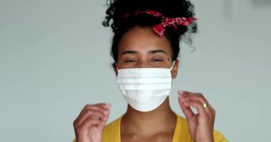 Young millennial mixed race woman removing face mask smiling at camera