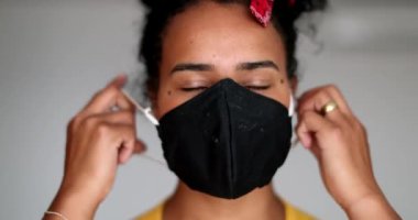 Happy young black woman taking off pandemic mask feeling relief
