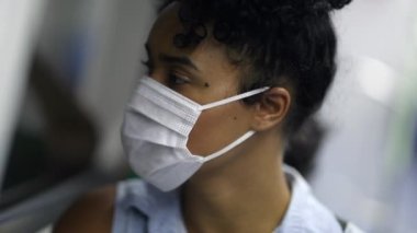Young woman riding metro wearing surgical mask. student or worker commuting in subway looking out window