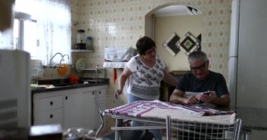 Karı koca cep telefonu ekranını kontrol etmek için arıyor. Son sınıf evli çift ev mutfağında.