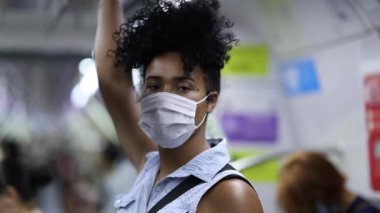 Young black woman in subway metro wearing surgical mask virus prevention. African american mixed race commuter