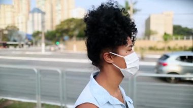 Racially diverse young woman walking in city with covid mask prevention