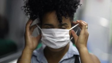 Young black African American woman putting surgical mask while riding metro subway