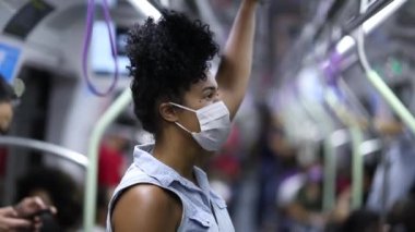 African american woman commuting in subway wearing surgical mask