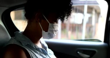 Arka koltuktaki takside salgın hastalık maskesi takan kız akıllı telefona bakıyor.