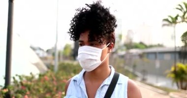 Millennial young black commuter woman walking wearing virus prevention mask