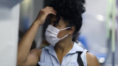 Young black woman in underground metro wearing pandemic mask
