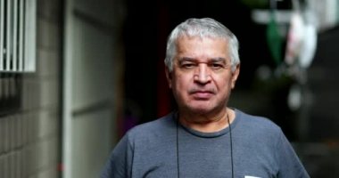 Ciddi bir yaşlı adam kameraya bakıyor. Sıradan bir son sınıf resmi, ciddi bir ifade.