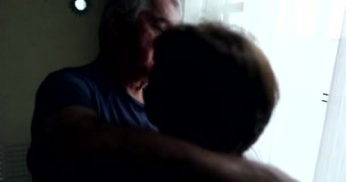Senior husband embracing wife by window, showing empathy