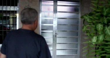 Old man arriving home, person opening front door