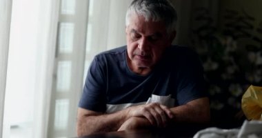 Bunalımda olan orta yaşlı bir adam evde oturup pencereden bakıyor.