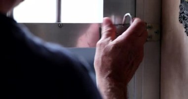 Kilidi kaldıran ve metal giriş kapısını açan kişi