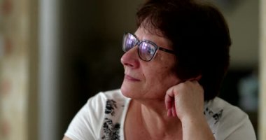 Orta yaşlı bir kadın kameraya bakıyor, yakın çekim.