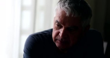 Preoccupied older man in shadows in contemplation and meditation