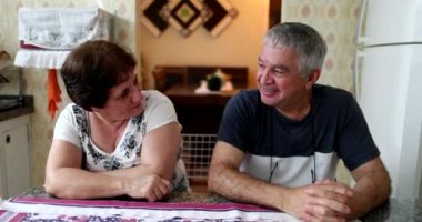 Married older couple sitting at home kitchen table, casual and real life